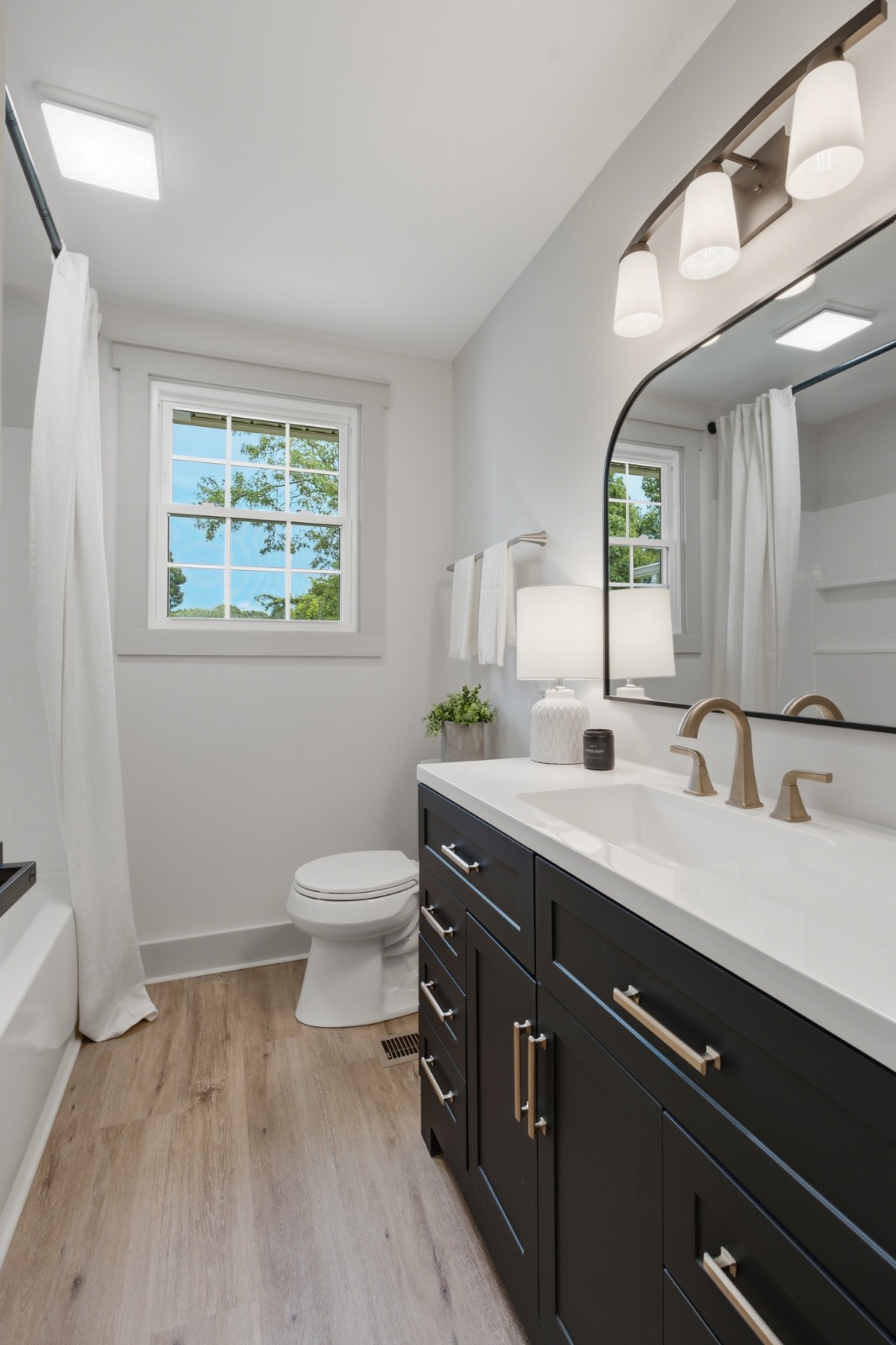 Dark bathroom vanity with white countertop and framed mirror
