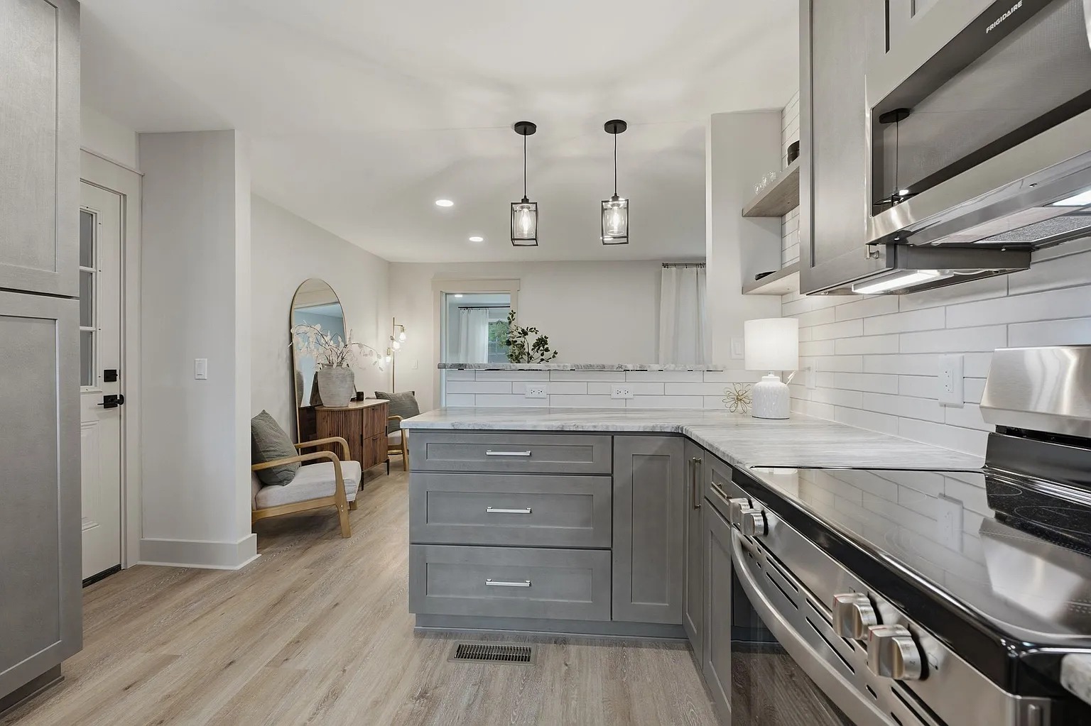 Grey kitchen cabinetry opening into a bright living area